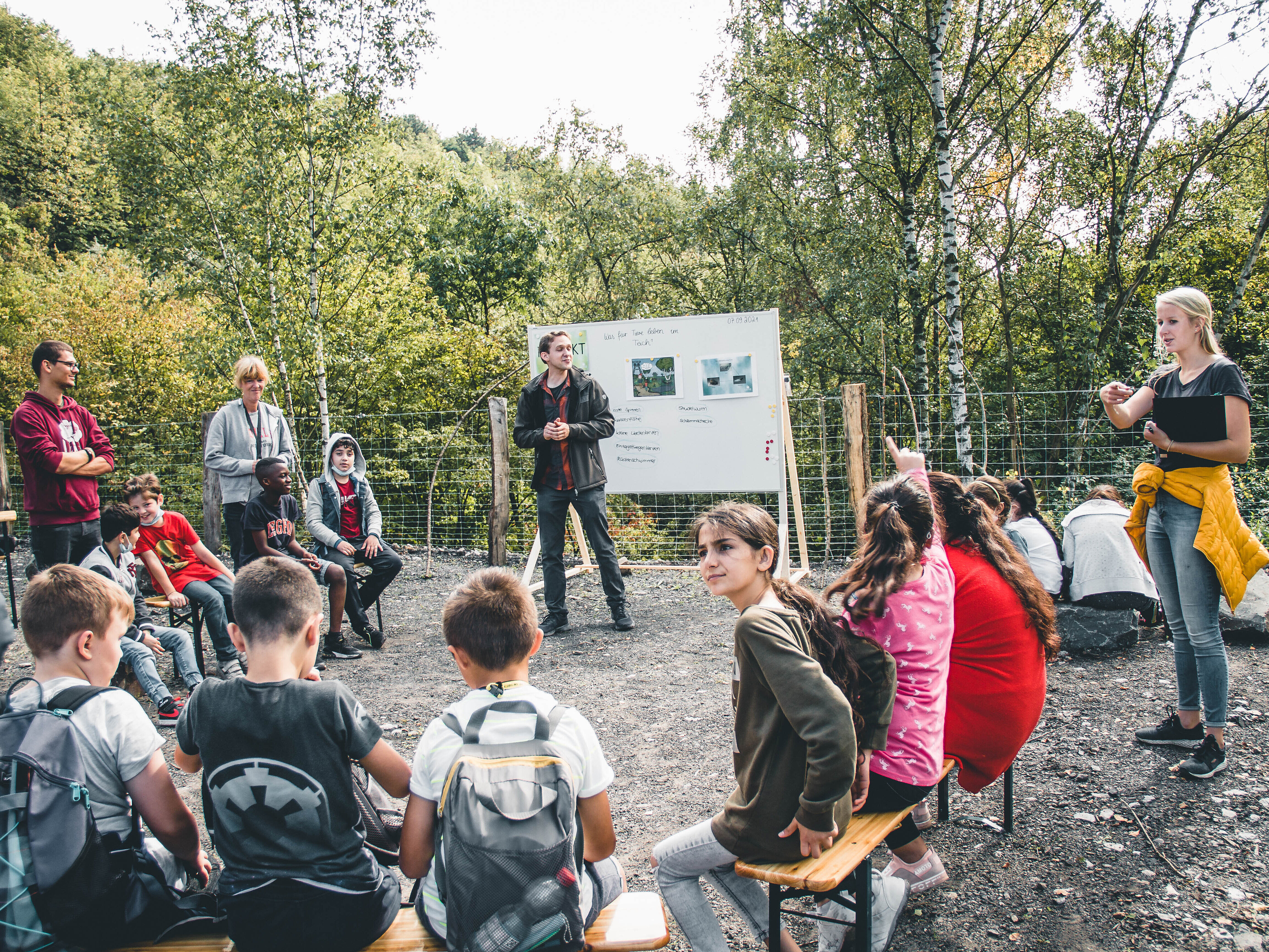 Schüler*innen lernen sitzen draußen in einem Halbreis vor einem Flipchart