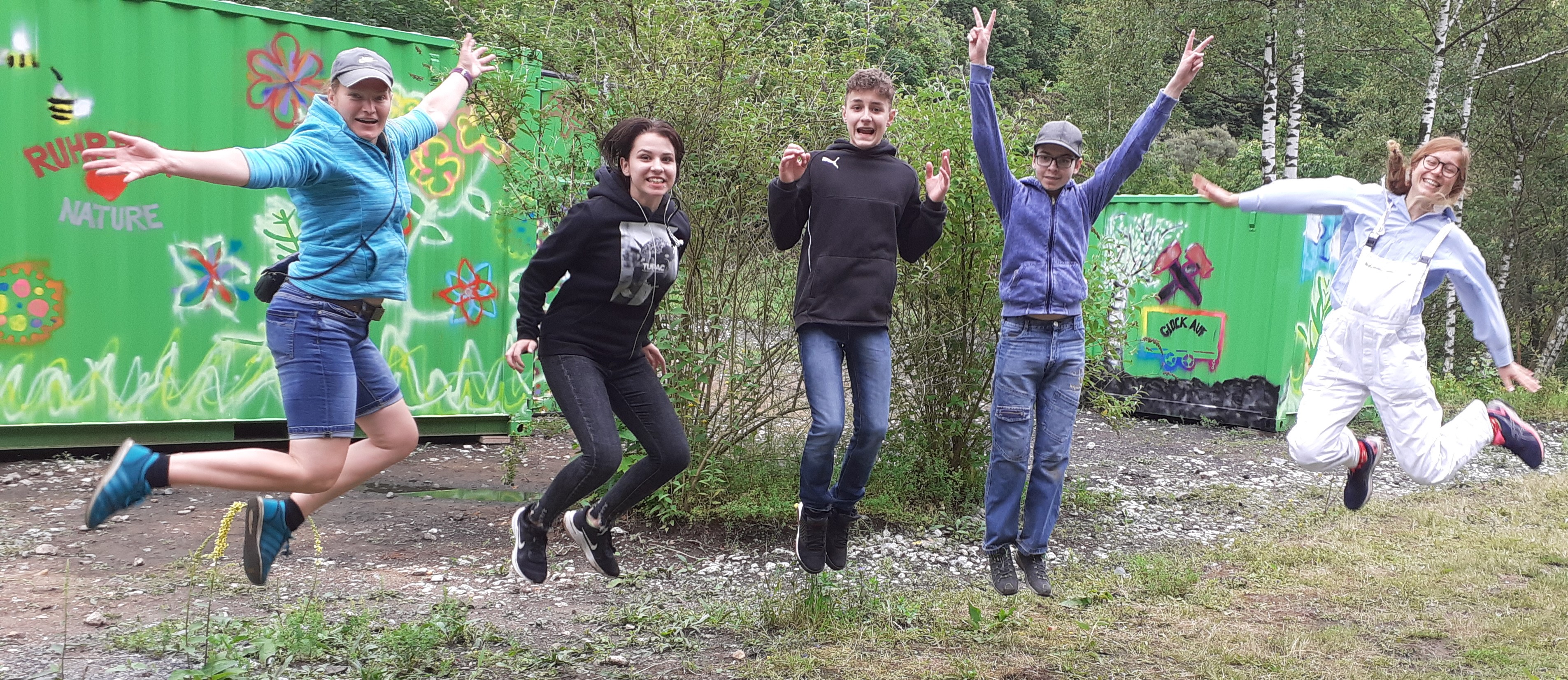 Fünf Personen springen freudig in die Luft.